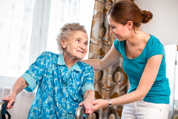 Altenpfleger(in) hilft betagter Frau aus dem Rollstuhl